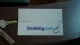 ホテルのフロントに置かれた封筒にBooking.comのロゴ、その上に釣り針。Booking.comを装うフィッシングメールのイメージ